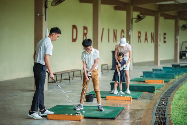 golfeur chinois asiatique de jeune couple enseignant leurs enfants jouant au golf au secteur de conduite de golf - golf golf swing putting cheerful photos et images de collection