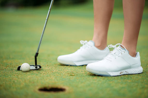 close-up de asiática jovem golfista feminina batendo na bola para um buraco de golfe no campo de golfe - golf women female concentration - fotografias e filmes do acervo