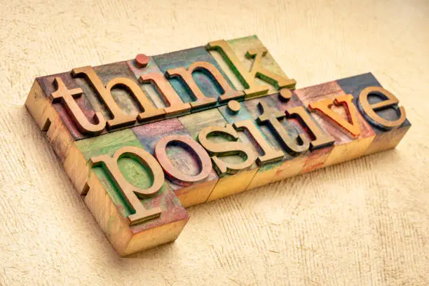 Think positive - word abstract in vintage letterpress wood type blocks against textured handmade paper, optimism, positivity and mindset concept