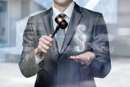 The concept of legality and justice. Lawyer with a hammer in his hands shows a paragraph on a blurred background.