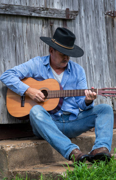 istock Man wearing cowboy hat playing guitar outside 1262399394