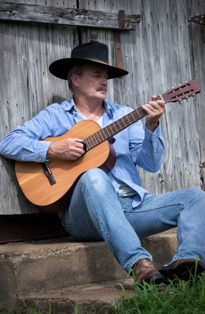 istock Man wearing cowboy hat playing guitar outside 1262399400