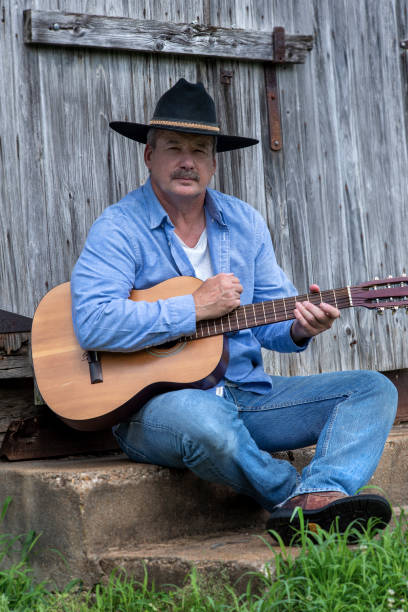 istock Man wearing cowboy hat playing guitar outside 1262399411