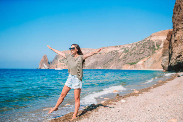 istock Young happy woman on the beach with mountain view 1262400596