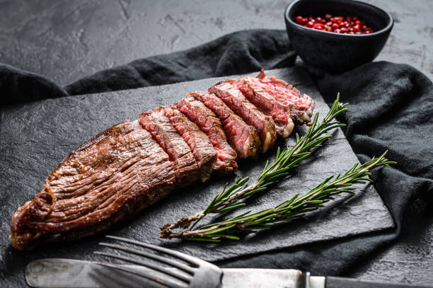 roasted medium rare sliced flank beef steak. black background. top view - flank steak imagens e fotografias de stock