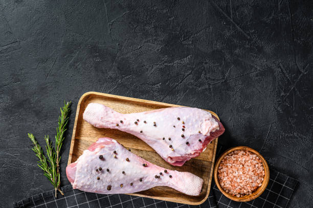 istock Raw chicken thigh with spices. Black background. Top view.  Space for text 1262401827