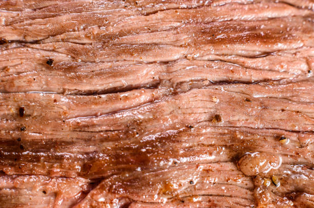 Grill Restaurant Beef Menu - Flank Steak on a black stone Board. Black background. Top view