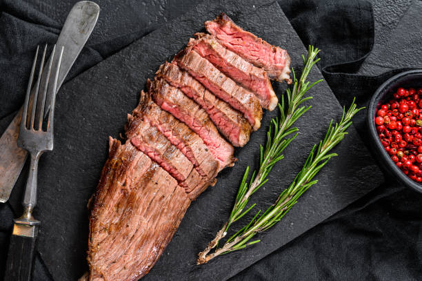 istock Steak of marbled beef roasting medium on a black stone Board. Black background. Top view 1262408057