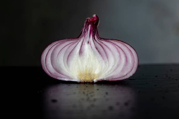 istock Red onion cut in half on a black stone board. Side view. 1262412493