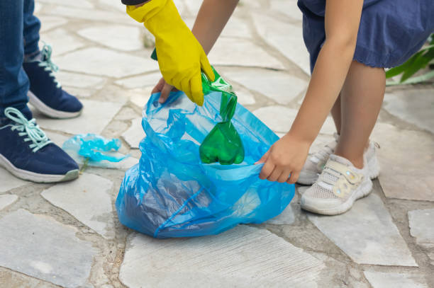 a woman and a girl (mom and daughter) with their hands collect garbage (plastic bottles) in a bag on the street (in the park). ecology. environmental protection concept - earth globe mother child imagens e fotografias de stock