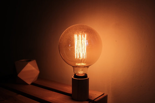 Lone Edison light bulb in a room, dark around