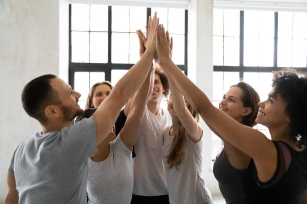 młodzi sportowi mieszani ludzie łączący ręce w powietrzu. - women sporting sport building exterior zdjęcia i obrazy z banku zdjęć