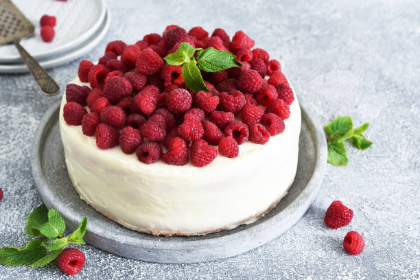 istock Birthday cake with cream and raspberries on a concrete kitchen background. 1262417927