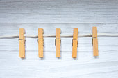 Light brown wooden clothes pegs scattered on a grey table. A group of clothespins.