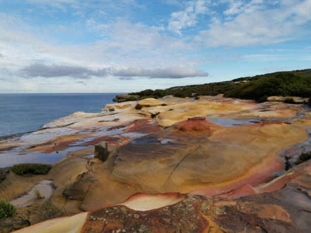 istock Beautiful coalstal trail with stunning rock formations and cliffs and reflections of blue sky on water puddles along the ocean front in the national park 1262423244