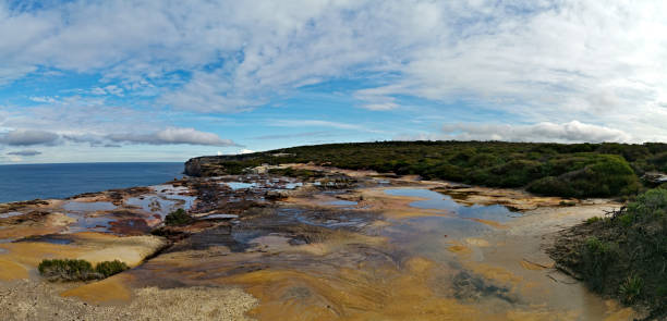 istock Beautiful coalstal trail with stunning rock formations and cliffs and reflections of blue sky on water puddles along the ocean front in the national park 1262423372
