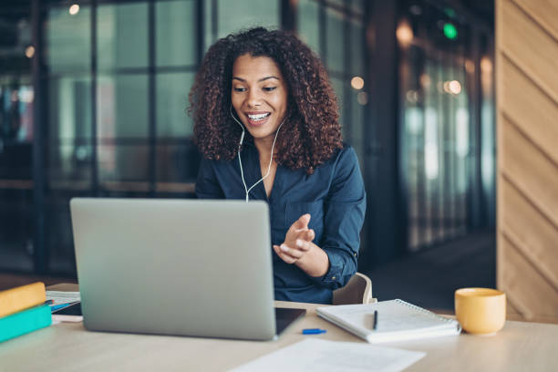Smiling businesswoman during a video call in the office Businesswoman with a laptop having a video call web conference photos stock pictures, royalty-free photos & images