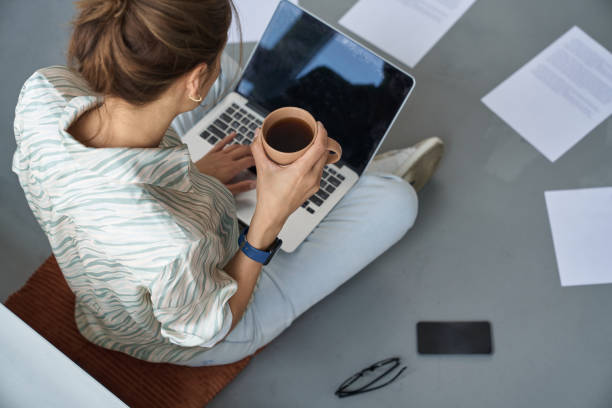 istock Woman with hot drink using laptop at home 1262436491