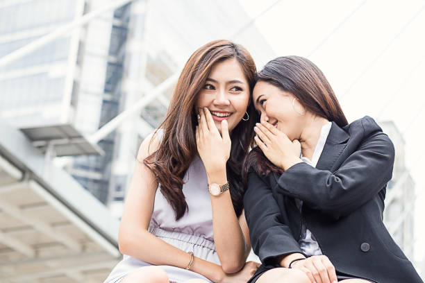 две сотрудницы шепчутся возле офиса (сплетни, офис, женщины) - whispering gossip women secrecy стоковые фото и изображения