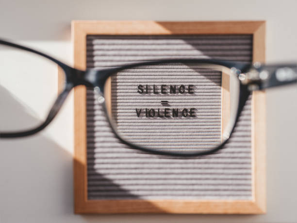 istock Top view on letter board with words Silence equal Violence through eyeglasses. Flat lay concept with actual statement. Social issue. Race problem in society. 1262444512