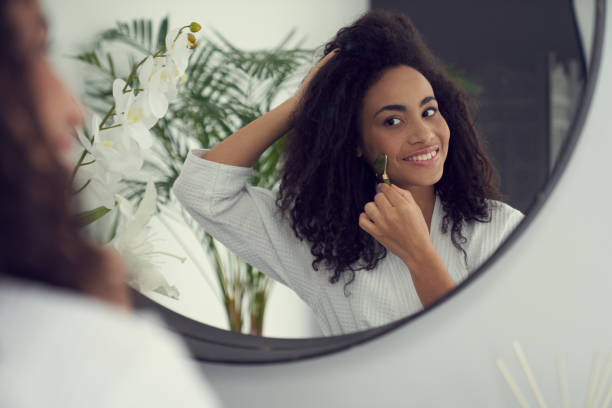 istock Smiling beautiful female using jade roller indoors 1262451258