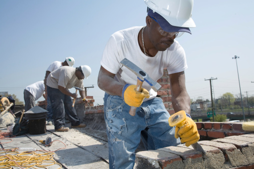 Bricklayer laying bricks on mortar on new residential house construction