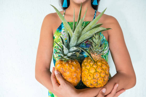 istock Hispanic Woman holding pineapple against white wall 1262478816