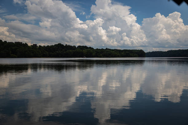 istock Reflection of puffy sky over a lake with forest on a distance 1262481492