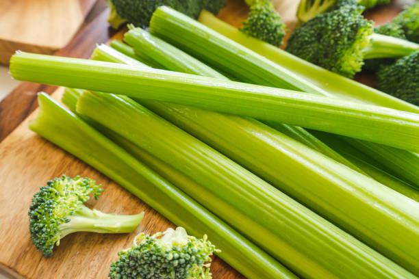 istock Celery and broccoli close up on wooden cutting board. 1262500881