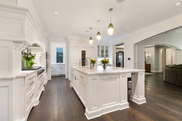 All white kitchen with dark brown wood flooring stock photo