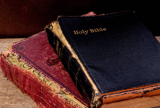 istock Old Bible and Red Book on Wood Table 1262541374