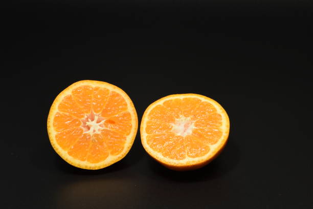 Sliced orange An orange sliced into two against a black backdrop sabby stock pictures, royalty-free photos & images