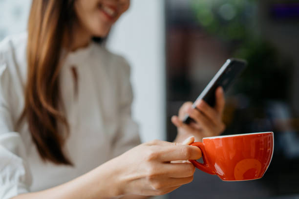 istock Young asian woman enjoying coffee and using smart phone 1262575275