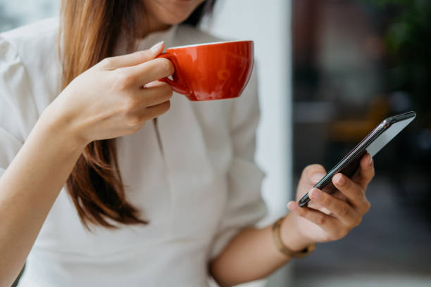 istock Young asian woman enjoying coffee and using smart phone 1262575556