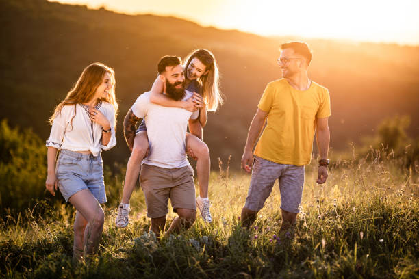 istock Happy friends talking while walking up the hill at sunset. 1262576272