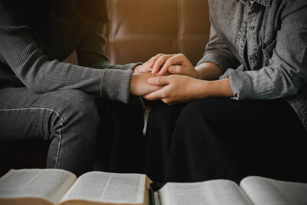 istock two women reading and study bible  in home and pray together. 1262576276