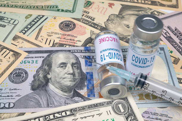 syringes and covid-19 vaccine ampoule lying on top of the US dollar. stock photo