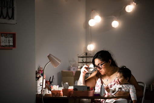 Madre trabajando desde casa en el escritorio mientras sostiene a su hija photo
