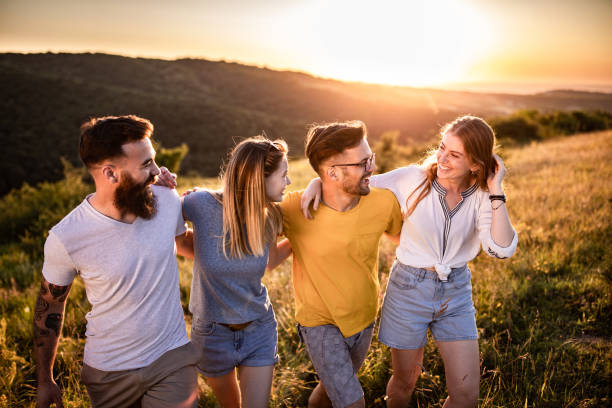 istock Happy embraced friends talking and walking on a hill at sunset. 1262580501