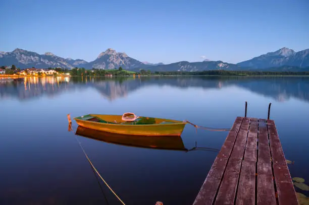 Hopfensee with rowing boat and wooden jetty, in the background the Tannheim Mountains, Allgäu, Bavaria, Germany