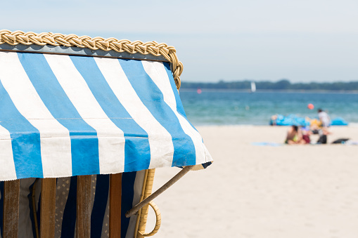Detail of a Strandkorb (wicker beach chair). Beach, the Baltic Sea and tourists in the background