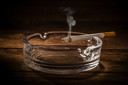 Glass of whiskey and rolled cigars on wooden table close up