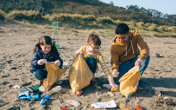 Young volunteers cleaning the beach Group of young volunteers picking up trash on the beach baby squatting stock pictures, royalty-free photos & images