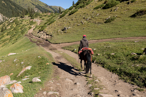 Altyn-Arashan, Kyrgyzstan, August 14 2018: A rider rides lonely on a path in the valley of Altyn-Arashan in Kyrgyzstan