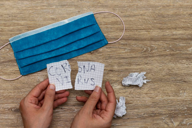 istock hands holding  tear paper with coronavirus concept and blue mask 1262595824