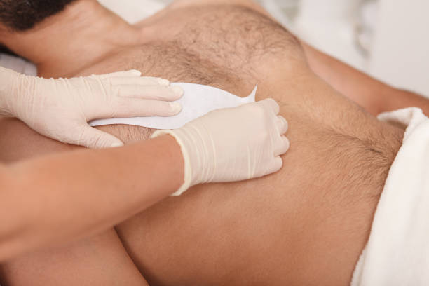 Man getting waxing hair removal at the salon Cosmetologist doing waxing on torso of unrecognizable male client epilator stock pictures, royalty-free photos & images