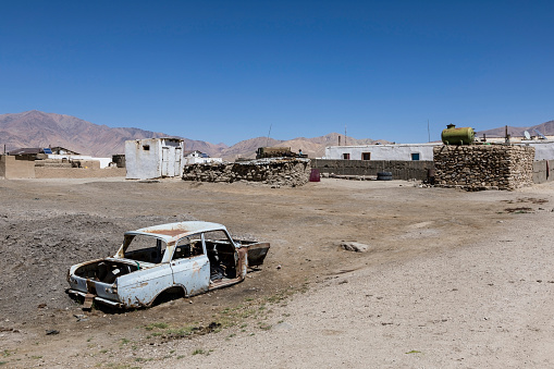Bulunkul, Tajikistan, August 23 2018: The secluded place Bulunkul with traditional clay and stone houses in the Pamir mountains. In the foreground a rusted car