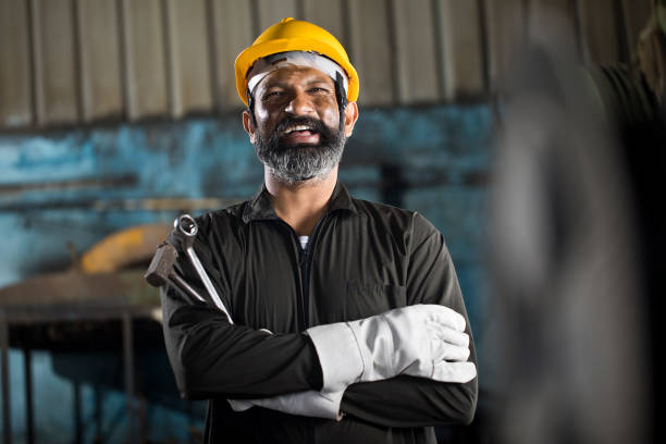 Happy industrial worker with work tool at factory