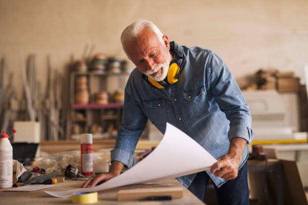istock Smiling senior carpenter holding a blueprint 1262611799