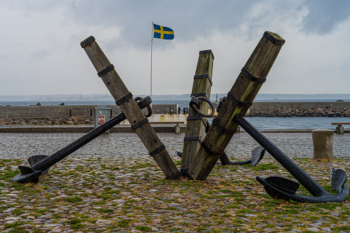 Three old anchors at Parapeten in Helsingborg, Sweden. This area has a long and close relationship with maritime activity. Swedish flag in the background